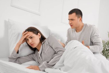 Stresli genç kadın ve kavgacı kocası yatak odasında.