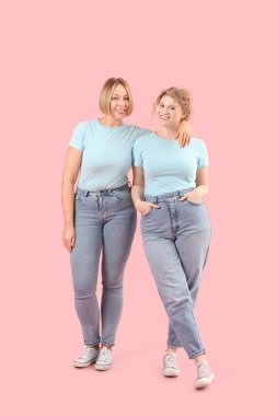 Pembe arka planda şık kotlu güzel mutlu kadınlar.