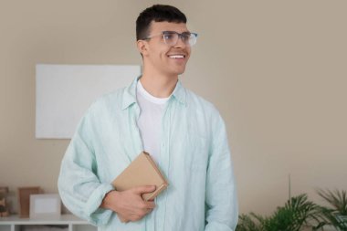 Yakışıklı, mutlu, gözlüklü, evde kitabı olan bir genç.