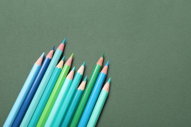 Yeşil arkaplanda parlak renkli kalemler kümesi