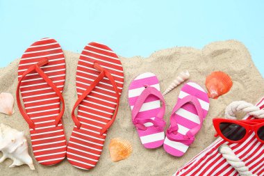 Renkli arka planda şık parmak arası terlikleri ve deniz kabukları olan kompozisyon