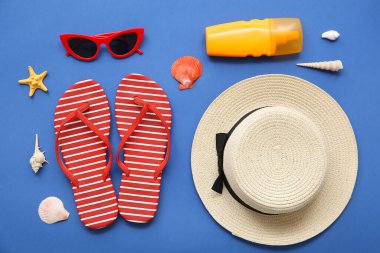 Mavi arka planda plaj aksesuarları ve deniz kabukları olan kompozisyon