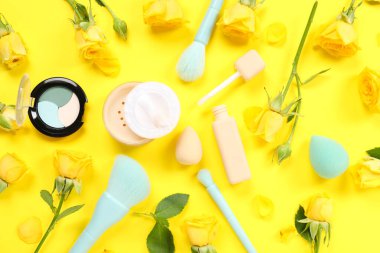 Sarı arka planda çiçekli ve dekoratif kozmetik ürünlü güzel kompozisyon, yakın plan.