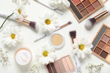 Beyaz arka planda çiçekler, fırçalar ve dekoratif kozmetik ürünleri ile güzel kompozisyon, yakın plan