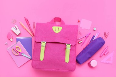 Şık okul çantalı kompozisyon ve pembe arka planda farklı kırtasiye malzemesi.