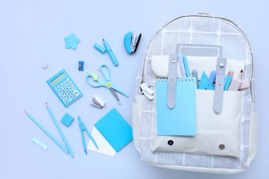 Renkli arka planda farklı kırtasiye malzemesi ve şık okul çantasına sahip kompozisyon