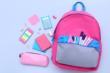 Renkli arka planda farklı kırtasiye malzemesi ve şık okul çantasına sahip kompozisyon