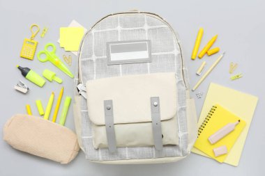 Okul çantalı kompozisyon ve gri arkaplanda farklı kırtasiye malzemesi