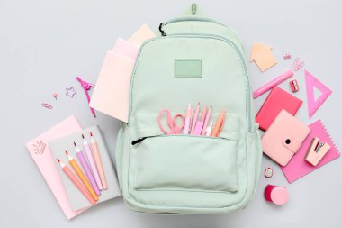 Gri arka planda farklı kırtasiye malzemesi ve şık okul çantasına sahip kompozisyon