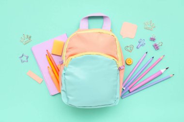 Renkli arka planda farklı kırtasiye malzemesi ve şık okul çantasına sahip kompozisyon