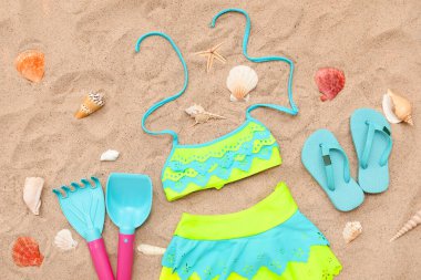 Çocuklar için plaj aksesuarları, parmak arası terlikler ve kumda mayo. Üst görünüm