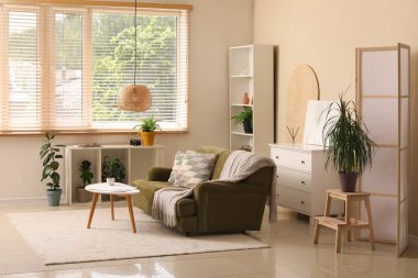 Güzel bir oturma odası, katlanır ekran, rahat bir kanepe, çekmeceler ve kahve masası.