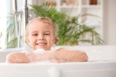 Küçük tatlı kız banyoda köpükle banyo yapıyor.