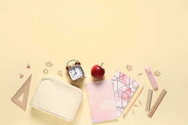 Lezzetli elma, çalar saat ve bej arka planda farklı okul kırtasiyesi.