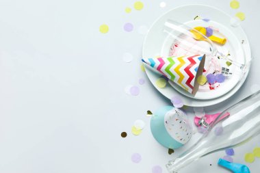 Kirli tabakları, boş şişesi ve gri arka planda parti dekoru olan kompozisyon