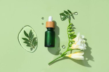 Gerekli yağ, frezya çiçeği ve su içeren bileşim renk arkaplanına düşer