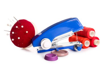 Beyaz arkaplanda iplik makaraları, düğmeler ve iğnelik izole edilmiş elle dikiş makinesi