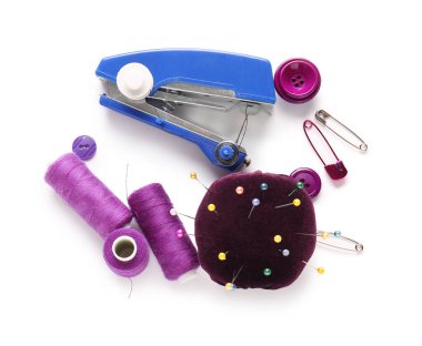 Beyaz arkaplanda iplik makaraları, düğmeler ve iğnelik izole edilmiş elle dikiş makinesi