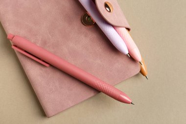 Kalemler bej arka planda deftere. Üst görünüm