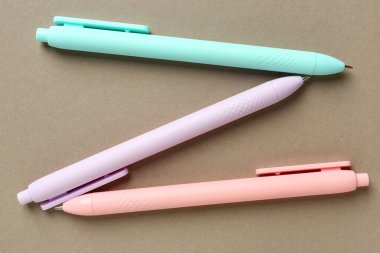 Bej arka planda üç renkli kalem. Üst görünüm