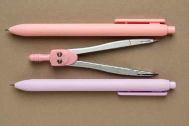 Bej arka planda pusula ve kalemler. Üst görünüm