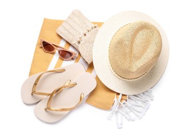 Havalı plaj şapkası, parmak arası terlik, güneş gözlüğü ve beyaz arka planda havlu.