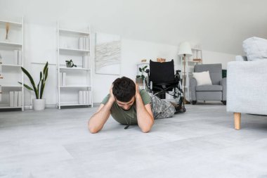 Travma sonrası stres bozukluğu olan genç bir asker evde yerde yatıyor.