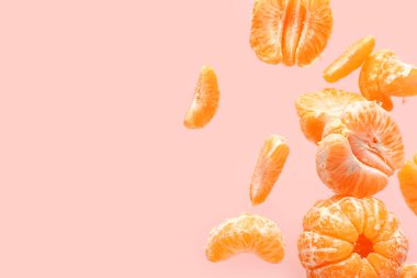 Pembe arka planda soyulmuş tatlı mandalinalar uçuyor