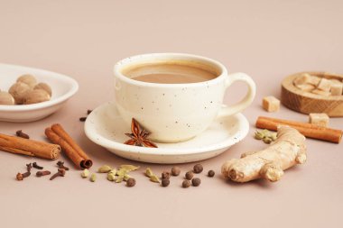 Kahverengi arka planda farklı baharat ve cevizli bir fincan lezzetli masala çayı.