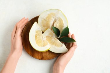 Beyaz arka planda kesilmiş taze aromalı ahşap bir tabakla kadın elleri.