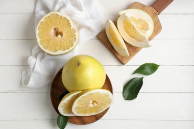 Tahta ve tabakta beyaz ahşap arka planda taze nar meyveleri var.