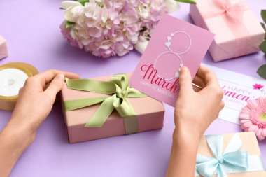 Hediye kutuları ve mor arka planda kartları olan kadın elleri. Uluslararası Kadınlar Günü