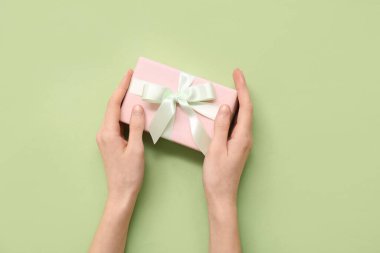 Yeşil arka planda pembe hediye kutusu olan kadın elleri. Uluslararası Kadınlar Günü