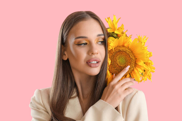 Молодая женщина с букетом красивых подсолнухов на розовом фоне