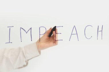 Beyaz arka planda keçeli kalemle IMPEACH yazan kadın
