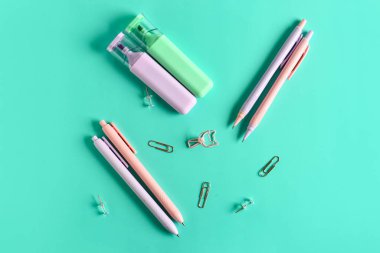 Kalemler ve ataçlar turkuaz arka planda