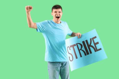 Yeşil arka planda kelime STRIKE ile pankart tutan genç adam protesto