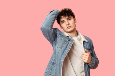 Pembe arka planda şık kot ceketli yakışıklı bir genç.