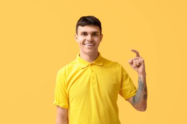 Sarı arka planda işaret dili kullanan genç sağır ve dilsiz adam.