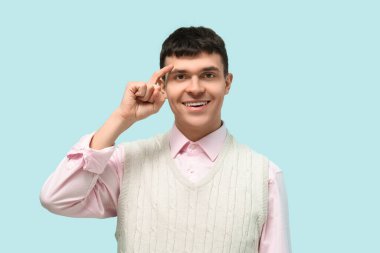 Mavi arka planda işaret dilini kullanan genç sağır ve dilsiz adam.