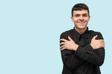 Mavi arka planda işaret dilini kullanan genç sağır ve dilsiz adam.