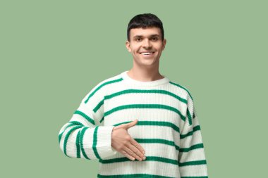 Yeşil arka planda işaret dilini kullanan genç sağır ve dilsiz adam.