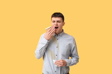 Turuncu arka planda gömleği lekeli uykulu genç bir adam.