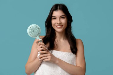 Mavi arka planda saç fırçası olan güzel genç bir kadın.