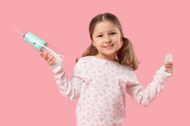 Ağız temizleyicisi ve pembe arka planda diş ipi olan tatlı küçük bir kız.