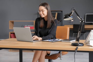 Genç sekreter ofiste modern bilgisayarla çalışıyor.