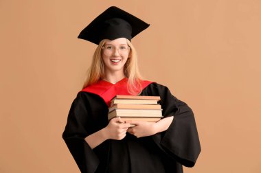 Kahverengi arkaplan üzerine kitapları olan havan tahtasındaki mezun bayan öğrenci.