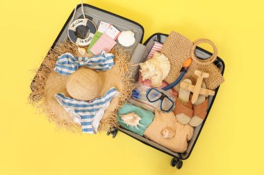 Sarı arka planda bavulu aç. Seyahat kavramı.