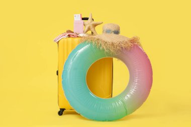 Çanta, şişirilebilir yüzük ve sarı arka planda plaj aksesuarları.