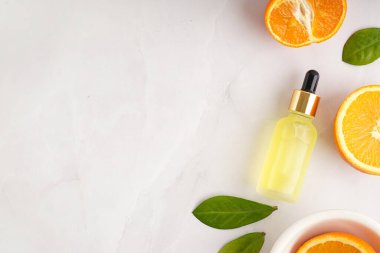 Gerekli yağ şişesiyle kompozisyon ve gri arka planda taze turuncu